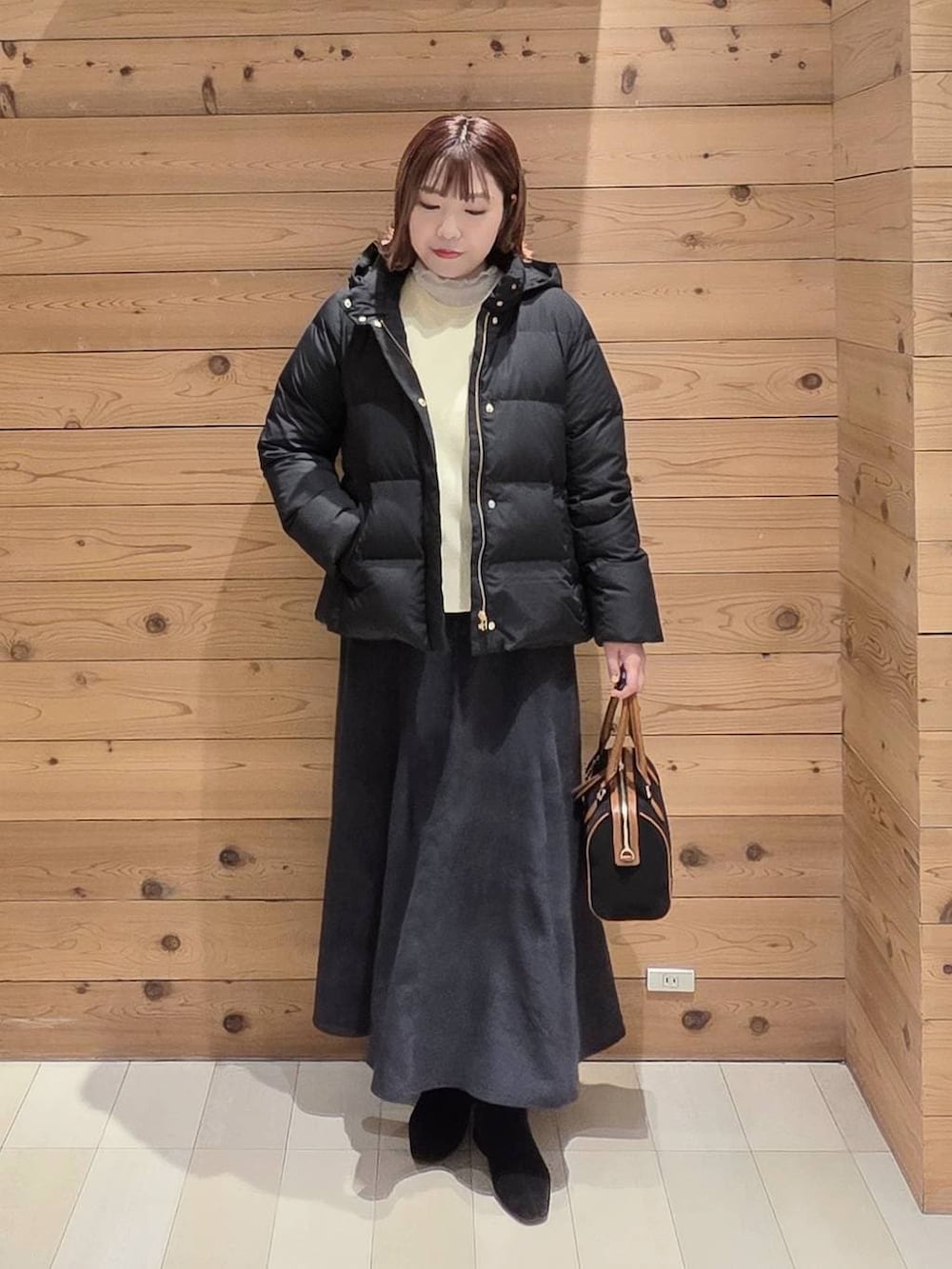 ブラック系のダウンジャケット/コート、グレー系のスカート、ブラック系のボストンバッグを着用したレディースの冬コーディネートの4枚目の写真