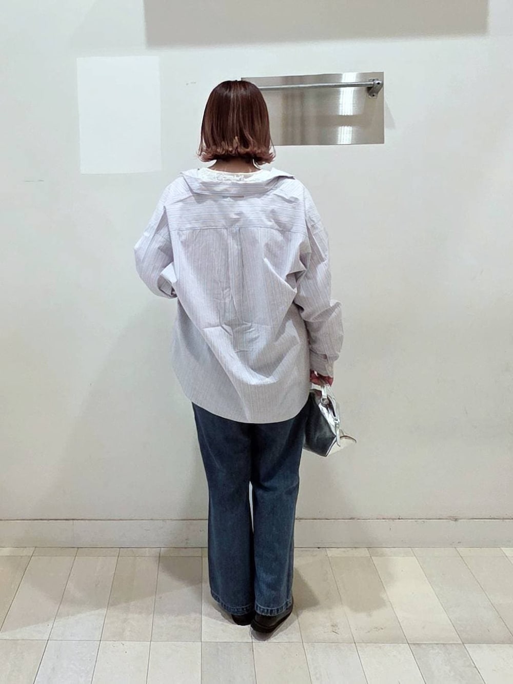 シルバー系のショルダーバッグ、ブラック系のローファー、ブルー系のデニムパンツを着用したレディースの春コーディネートの3枚目の写真