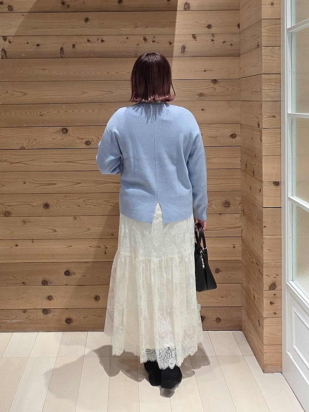 ブラック系のショルダーバッグ、ブルー系のダウンジャケット/コート、ホワイト系のTシャツ/カットソーを着用したレディースの冬コーディネートの2枚目の写真