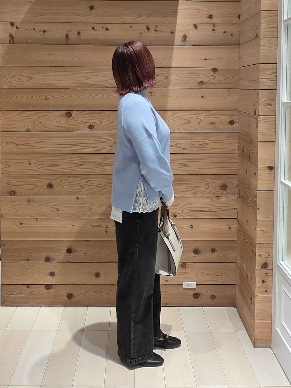 ブラック系のローファー、ホワイト系のショルダーバッグ、ブラック系のデニムパンツを着用したレディースの冬コーディネートの2枚目の写真