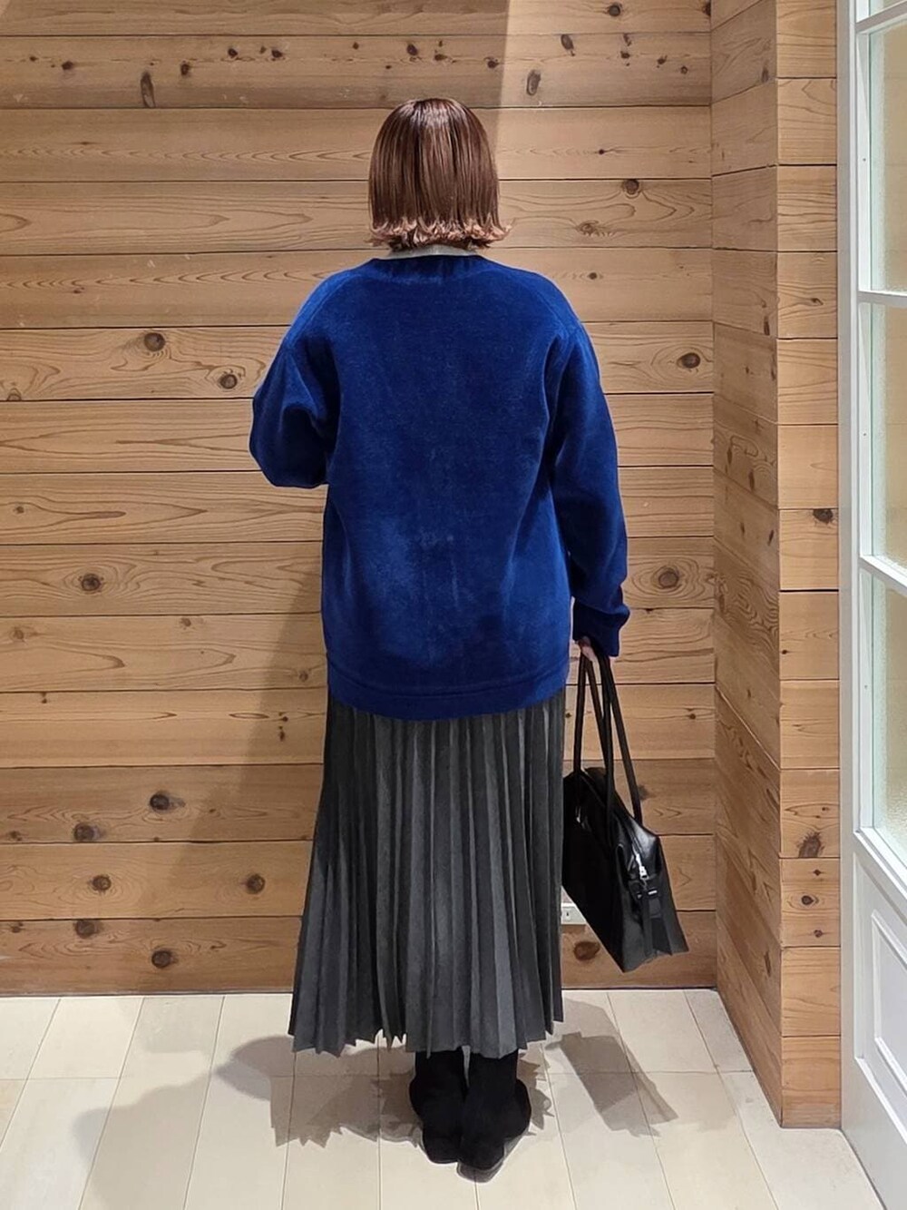 ブラック系のダウンジャケット/コート、ブラック系のボストンバッグ、グレー系のニット/セーターを着用したレディースの冬コーディネートの3枚目の写真