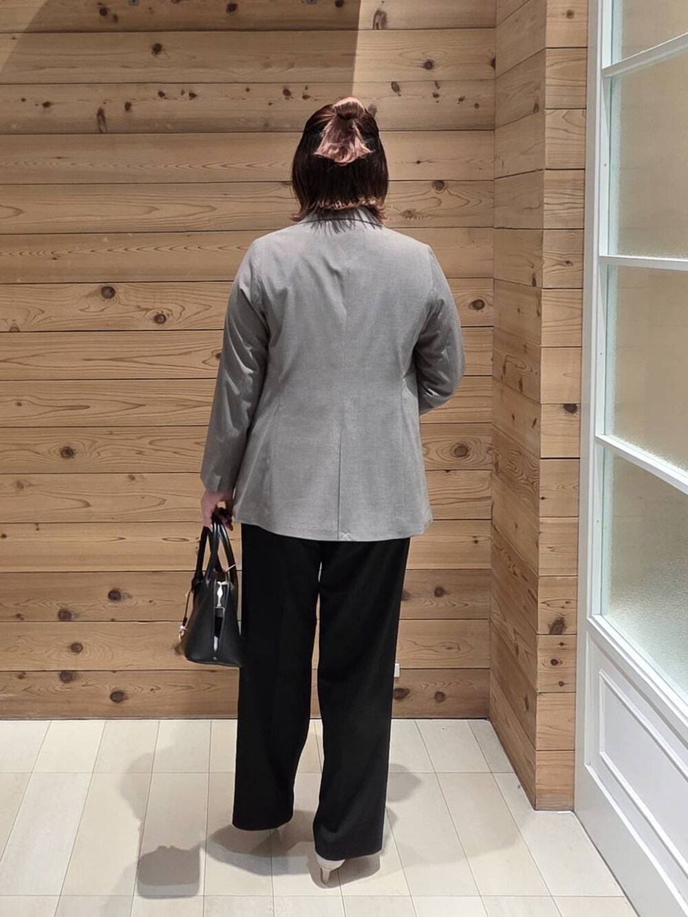 ブラック系のショルダーバッグ、ホワイト系のパンプス、ブラック系のスラックスを着用したレディースの冬コーディネートの3枚目の写真