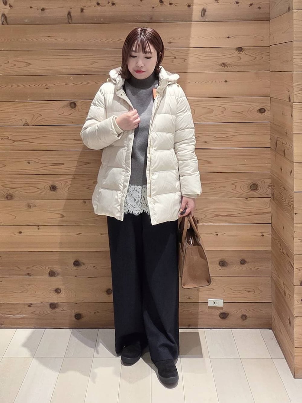 ベージュ系のダウンジャケット/コート、ベージュ系のショルダーバッグ、グレー系のニット/セーターを着用したレディースの冬コーディネートの4枚目の写真