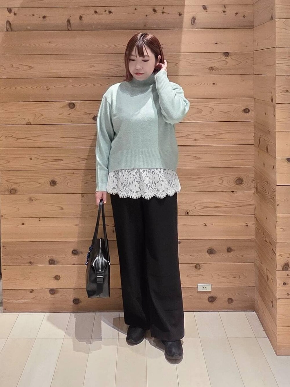 ブラウン系のダウンジャケット/コート、ブラック系のボストンバッグ、グリーン系のニット/セーターを着用したレディースの冬コーディネートの4枚目の写真