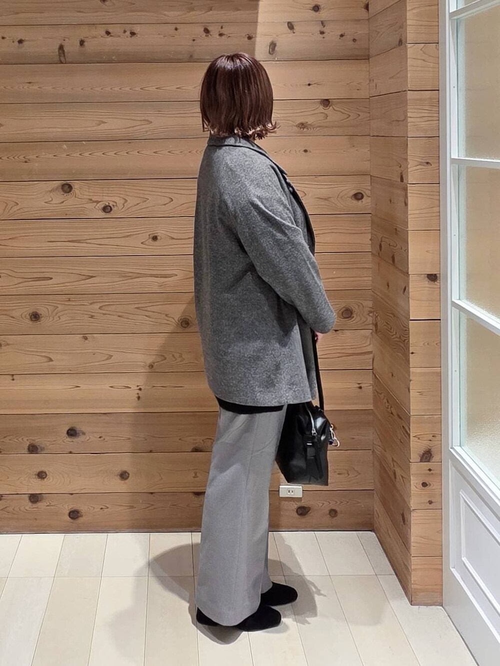 ブラック系のボストンバッグ、グレー系のチェスターコート、ブラック系のニット/セーターを着用したレディースの冬コーディネートの2枚目の写真