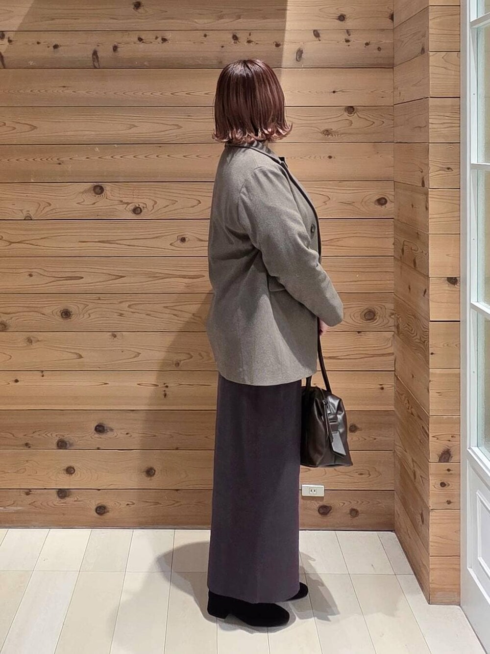 ブラウン系のボストンバッグ、グレー系のワンピース、ホワイト系のTシャツ/カットソーを着用したレディースの冬コーディネートの2枚目の写真