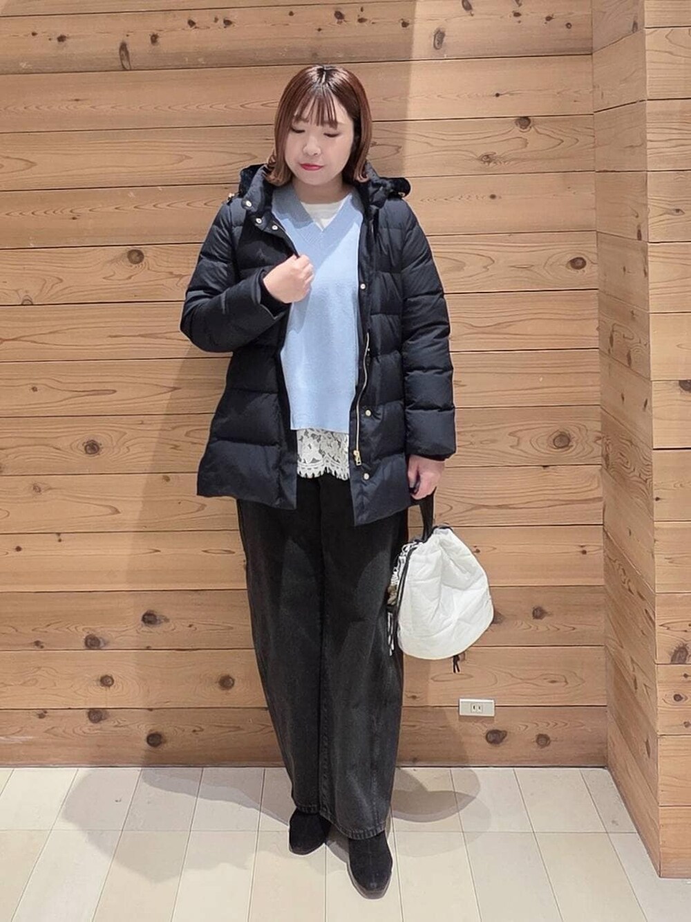 ブルー系のダウンジャケット/コート、ブラック系のデニムパンツ、ホワイト系のハンドバッグを着用したレディースの冬コーディネートの4枚目の写真