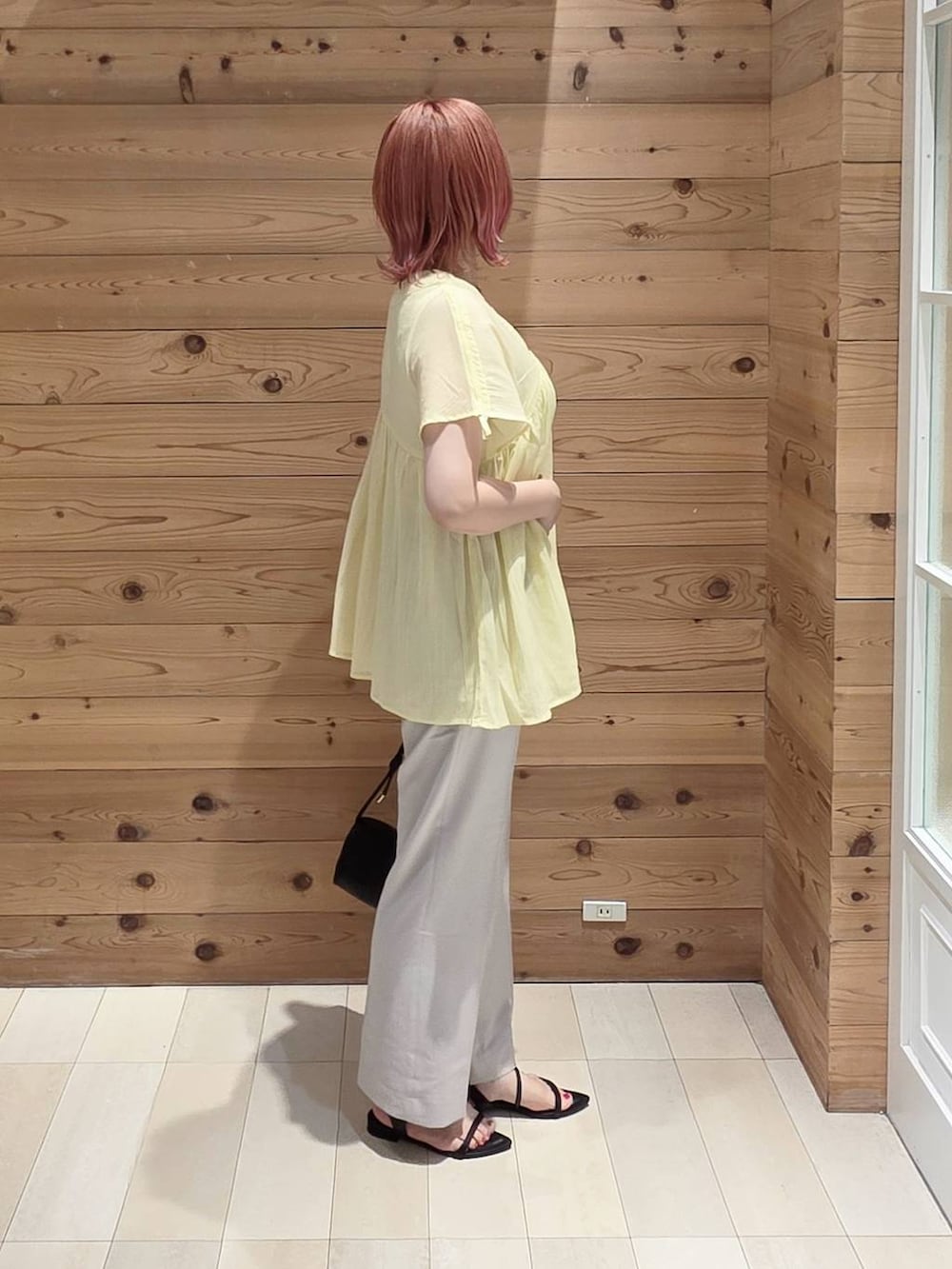 ブラック系のショルダーバッグ、グレー系のその他パンツ、イエロー系のシャツ/ブラウスを着用したレディースの夏コーディネートの2枚目の写真