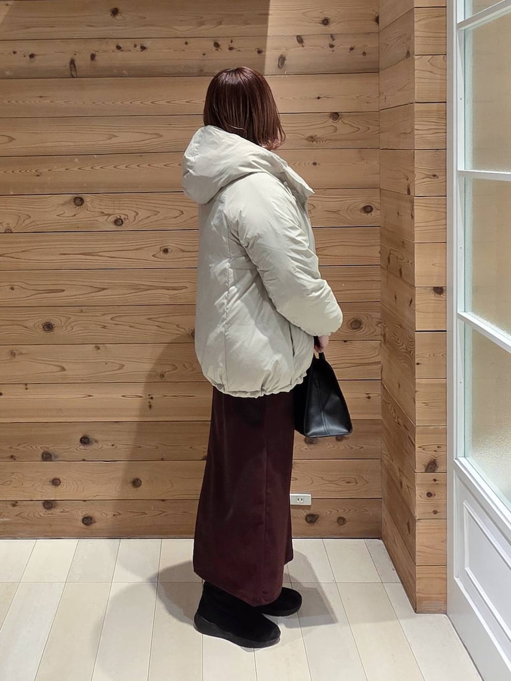 ベージュ系のダウンジャケット/コート、レッド系のスカート、ブラック系のブーツを着用したレディースの冬コーディネートの2枚目の写真