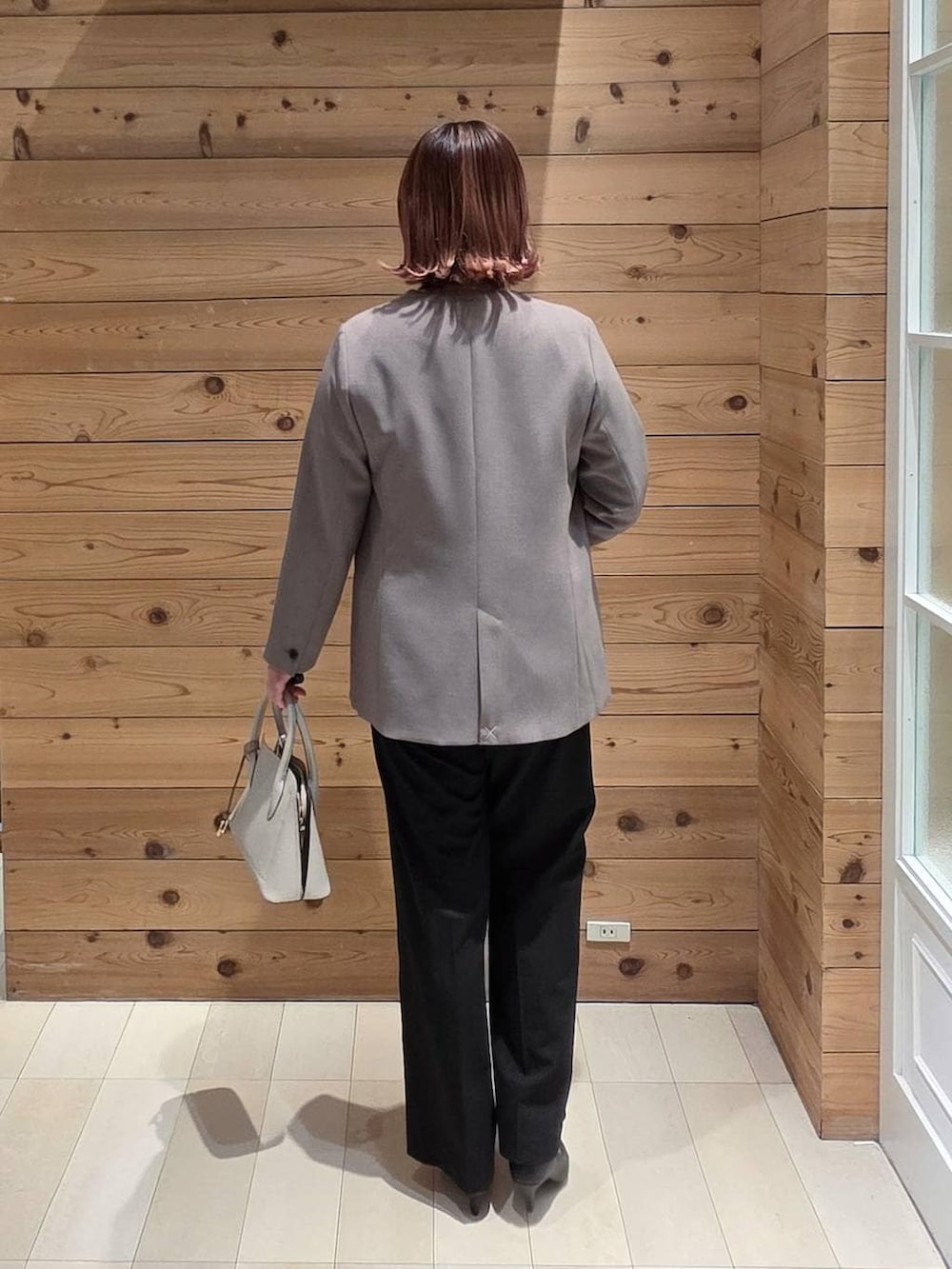 ホワイト系のショルダーバッグ、ブラック系のパンプス、ブラック系のスラックスを着用したレディースの冬コーディネートの3枚目の写真