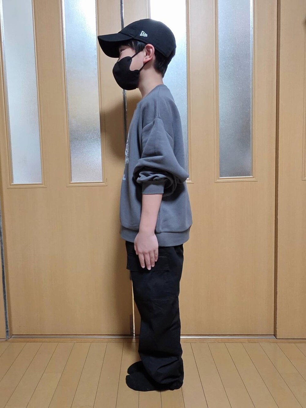 ブラック系のカーゴパンツ、グレー系のスウェット、ブラック系のキャップを着用したキッズの秋コーディネートの2枚目の写真