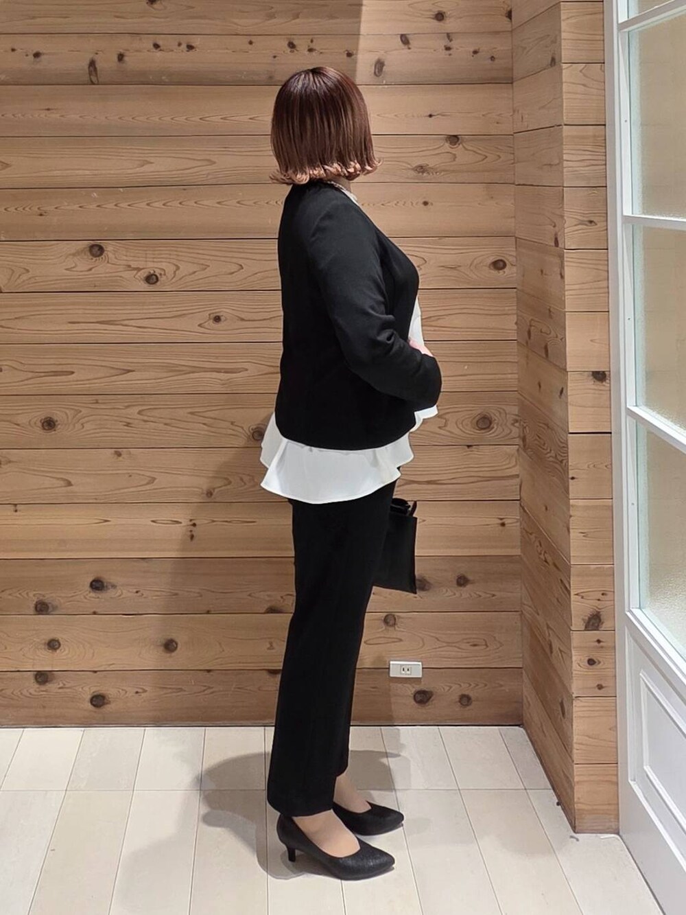 ブラック系のセットアップ、ブラック系のショルダーバッグ、ゴールド系のネックレスを着用したレディースの冬コーディネートの2枚目の写真