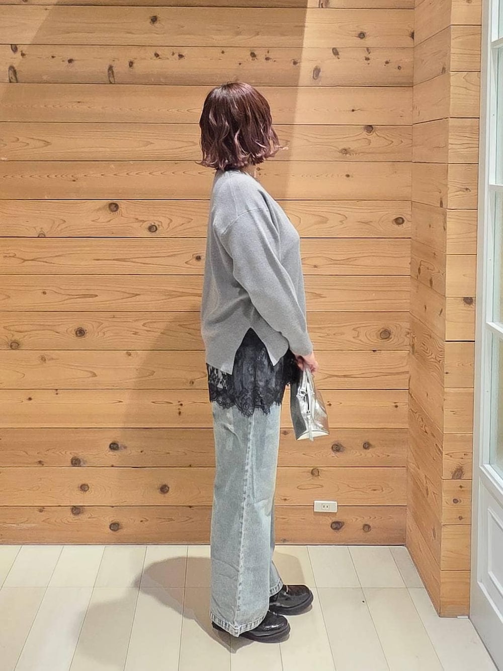 シルバー系のショルダーバッグ、ブラック系のローファー、ブルー系のデニムパンツを着用したレディースの冬コーディネートの2枚目の写真