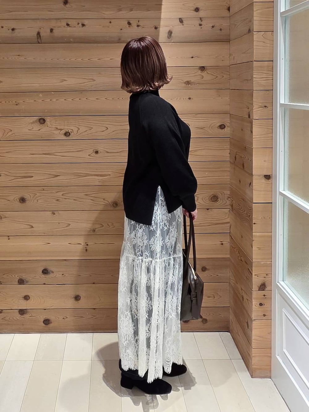 ブラウン系のボストンバッグ、ブルー系のデニムパンツ、ブラウン系のチェスターコートを着用したレディースの冬コーディネートの2枚目の写真