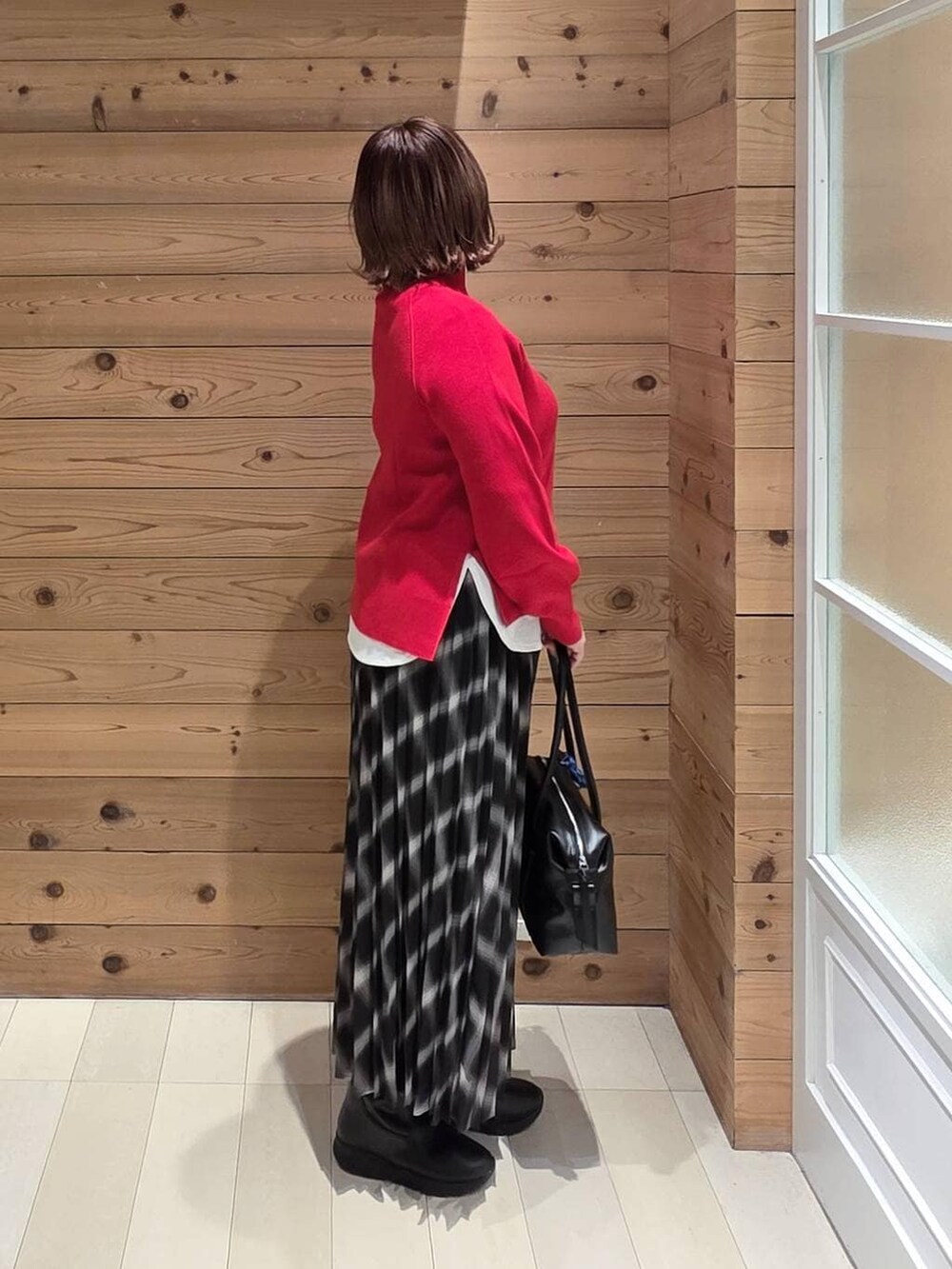 ブラック系のボストンバッグ、ベージュ系のブルゾン、ブラック系のブーツを着用したレディースの冬コーディネートの2枚目の写真