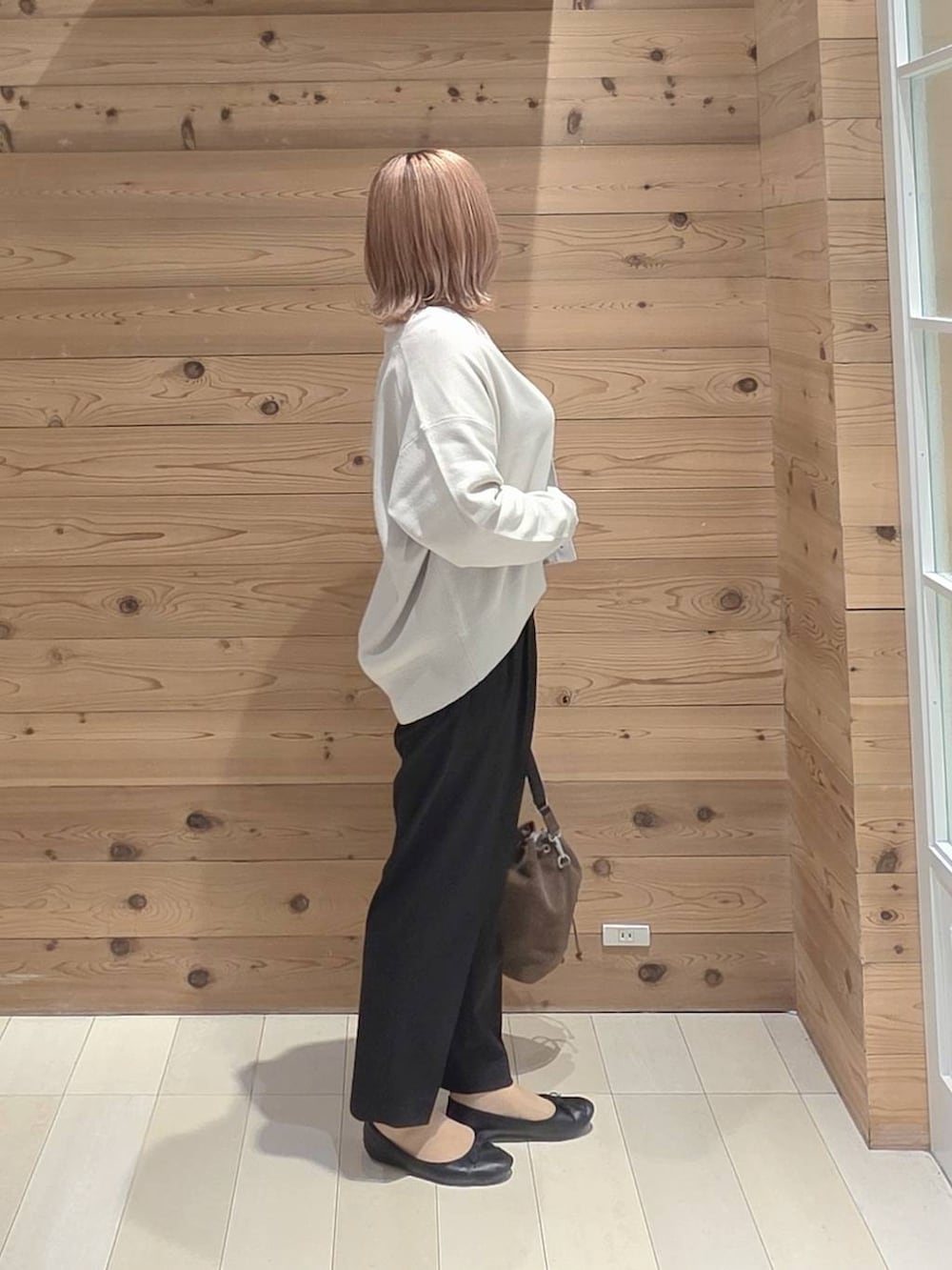 ブラウン系のショルダーバッグ、ブラック系のバレエシューズ、ホワイト系のTシャツ/カットソーを着用したレディースの秋コーディネートの2枚目の写真