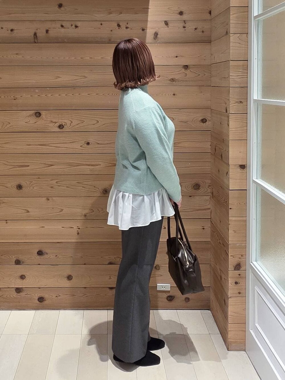 ベージュ系のブルゾン、ブラウン系のボストンバッグ、グリーン系のニット/セーターを着用したレディースの冬コーディネートの2枚目の写真