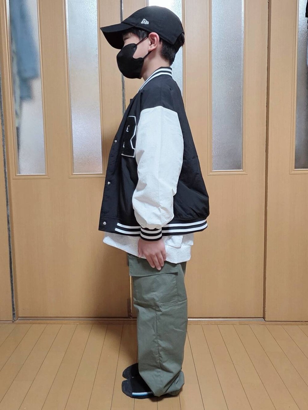 グリーン系のカーゴパンツ、ブラック系のブルゾン、グレー系のスウェットを着用したキッズの秋コーディネートの2枚目の写真