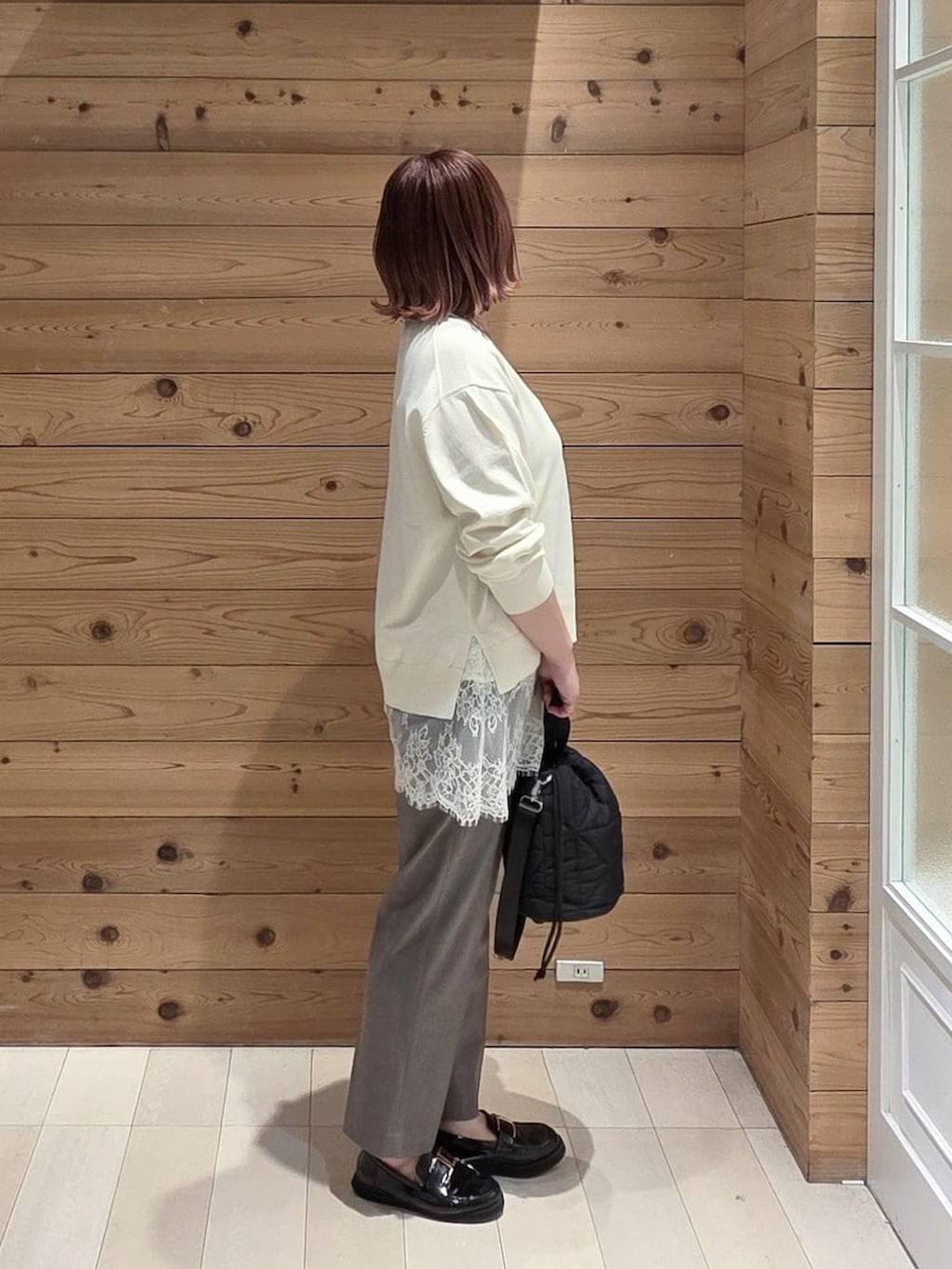 ブラック系のローファー、ブラック系のハンドバッグ、ブラウン系のスラックスを着用したレディースの春コーディネートの2枚目の写真