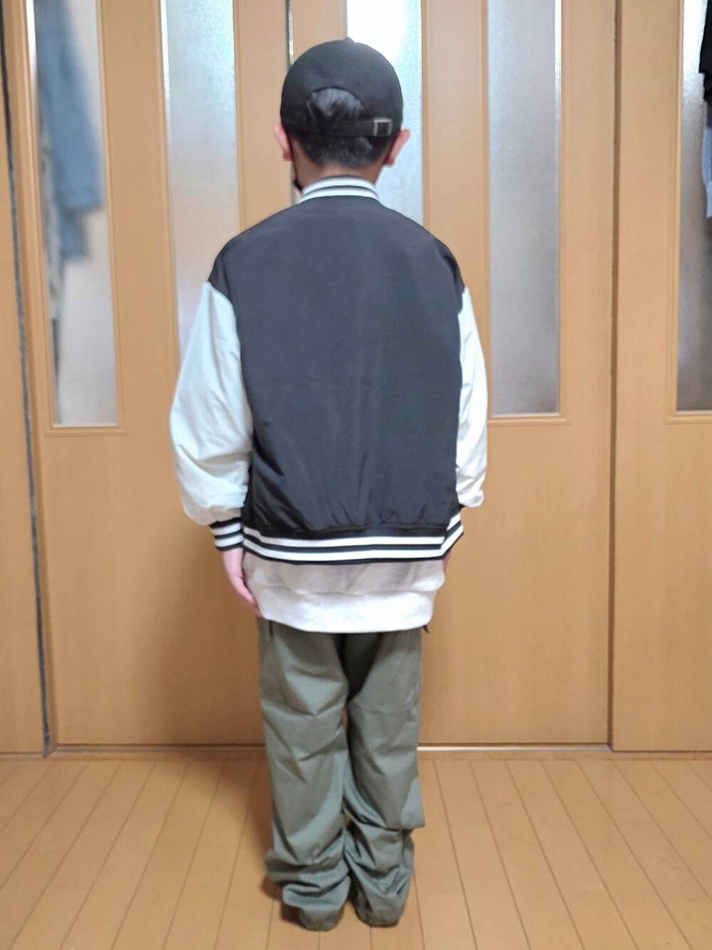 グリーン系のカーゴパンツ、ブラック系のブルゾン、グレー系のスウェットを着用したキッズの秋コーディネートの3枚目の写真