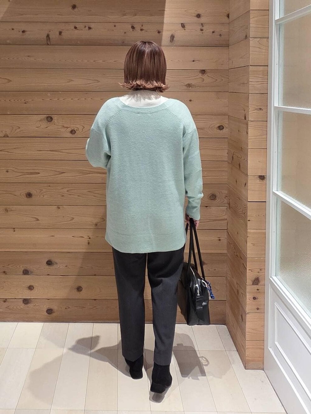 ブラック系のボストンバッグ、ブラック系のダウンジャケット/コート、ホワイト系のニット/セーターを着用したレディースの秋コーディネートの3枚目の写真