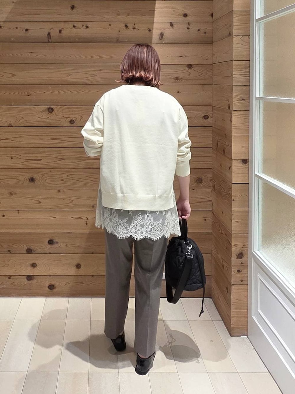 ブラック系のローファー、ブラック系のハンドバッグ、ブラウン系のスラックスを着用したレディースの春コーディネートの3枚目の写真