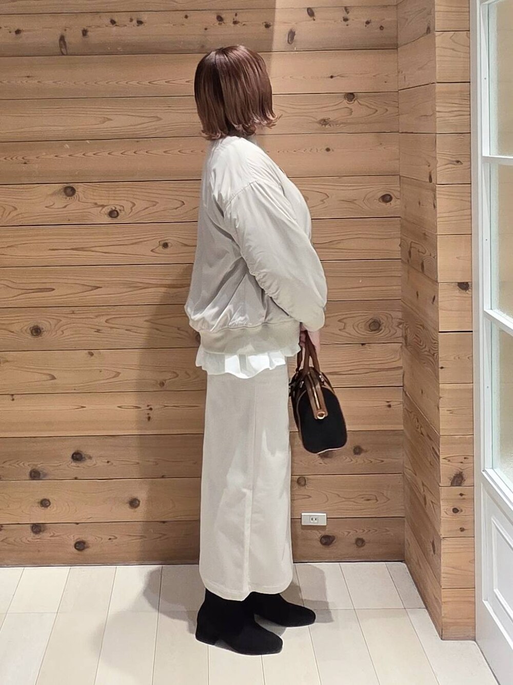 グレー系のニット/セーター、ベージュ系のブルゾン、グレー系のスカートを着用したレディースの冬コーディネートの2枚目の写真