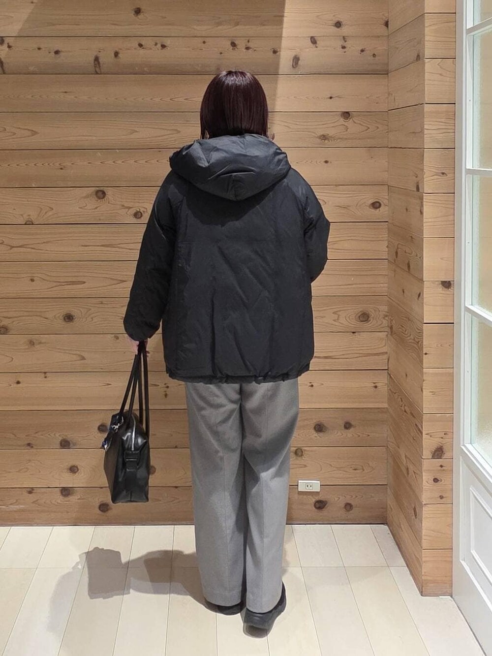 ブラック系のダウンジャケット/コート、ブラック系のボストンバッグ、ブラック系のブーツを着用したレディースの冬コーディネートの3枚目の写真