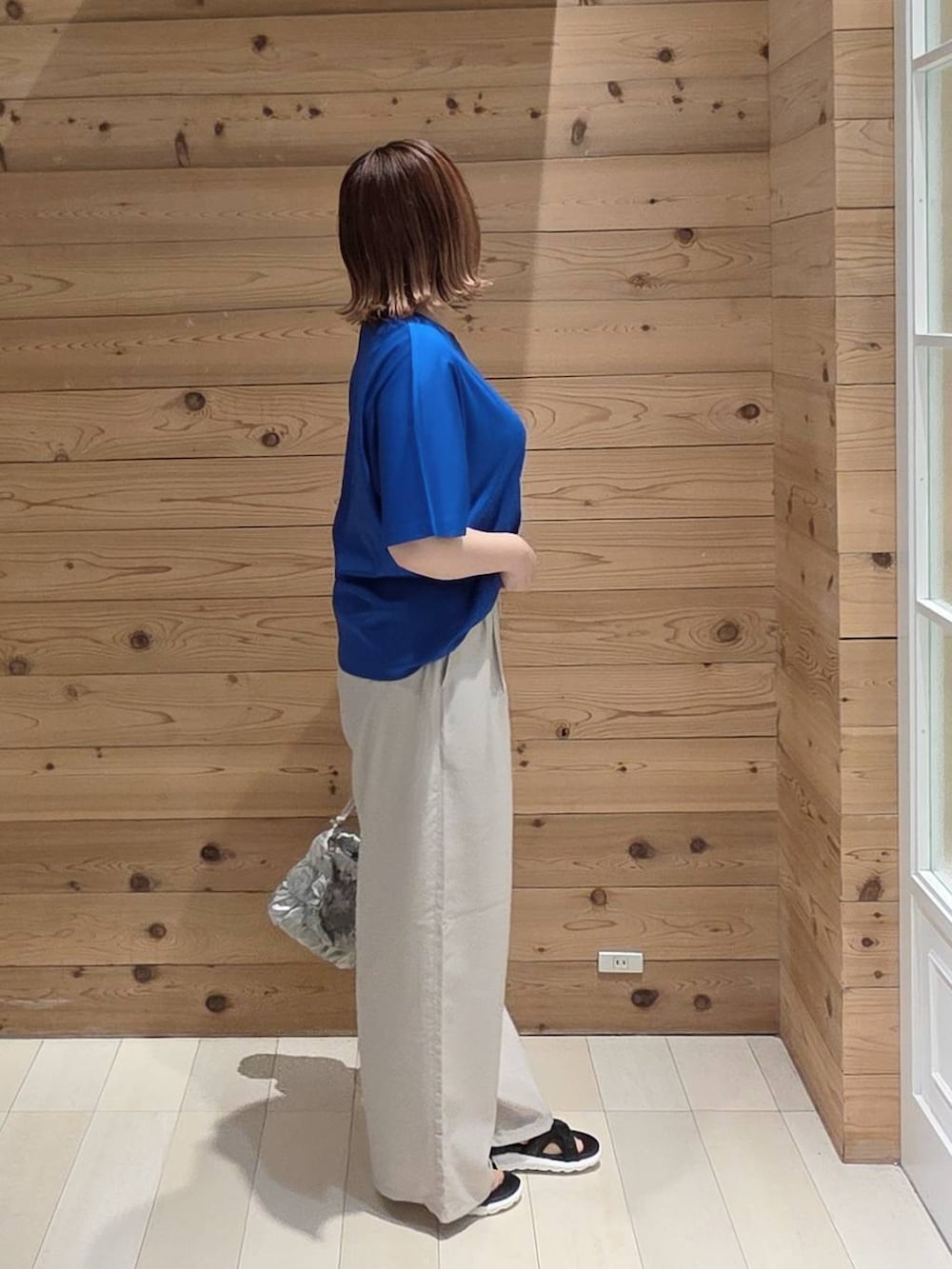 ベージュ系のその他パンツ、ブルー系のTシャツ/カットソー、ブラック系のサンダルを着用したレディースの夏コーディネートの2枚目の写真