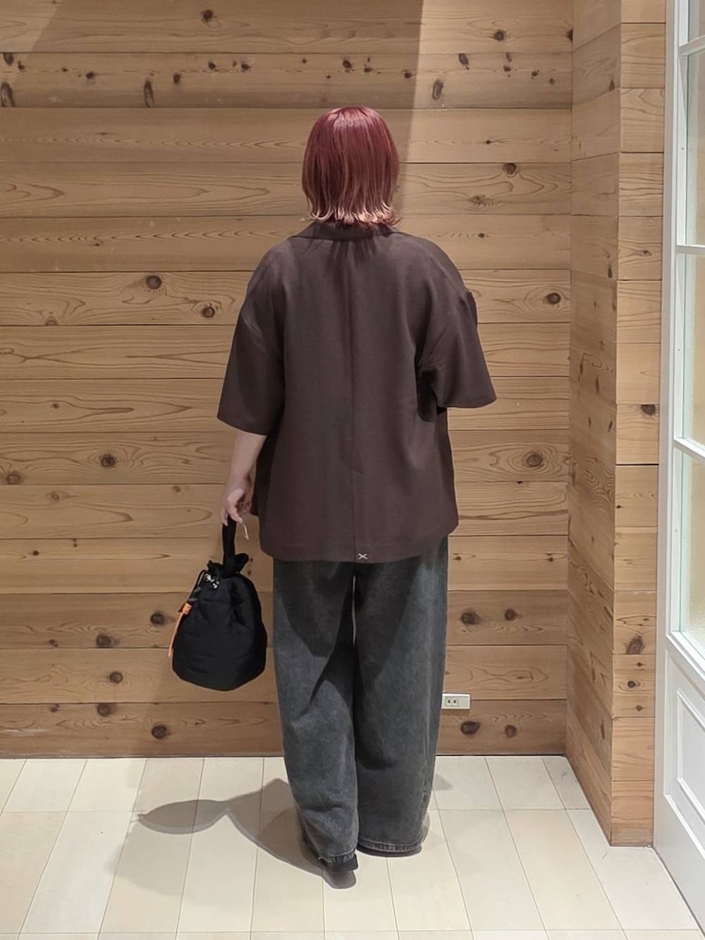ブラック系のハンドバッグ、ブラック系のデニムパンツ、ブラウン系のテーラードジャケットを着用したレディースの夏コーディネートの3枚目の写真
