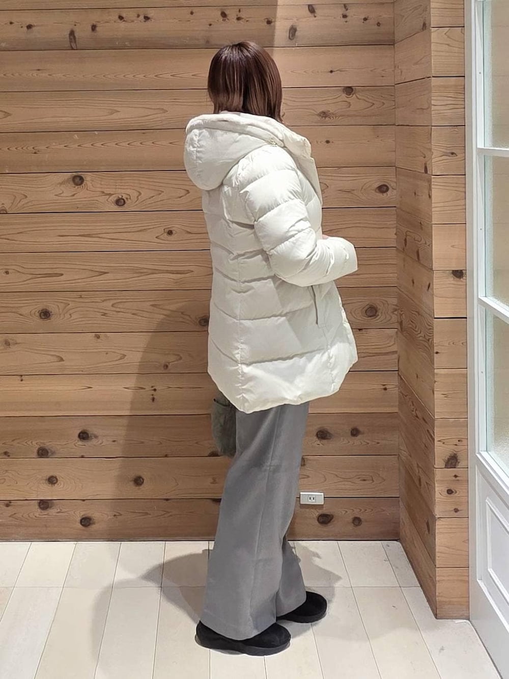 グリーン系のトートバッグ、ベージュ系のダウンジャケット/コート、ブラック系のブーツを着用したレディースの冬コーディネートの2枚目の写真