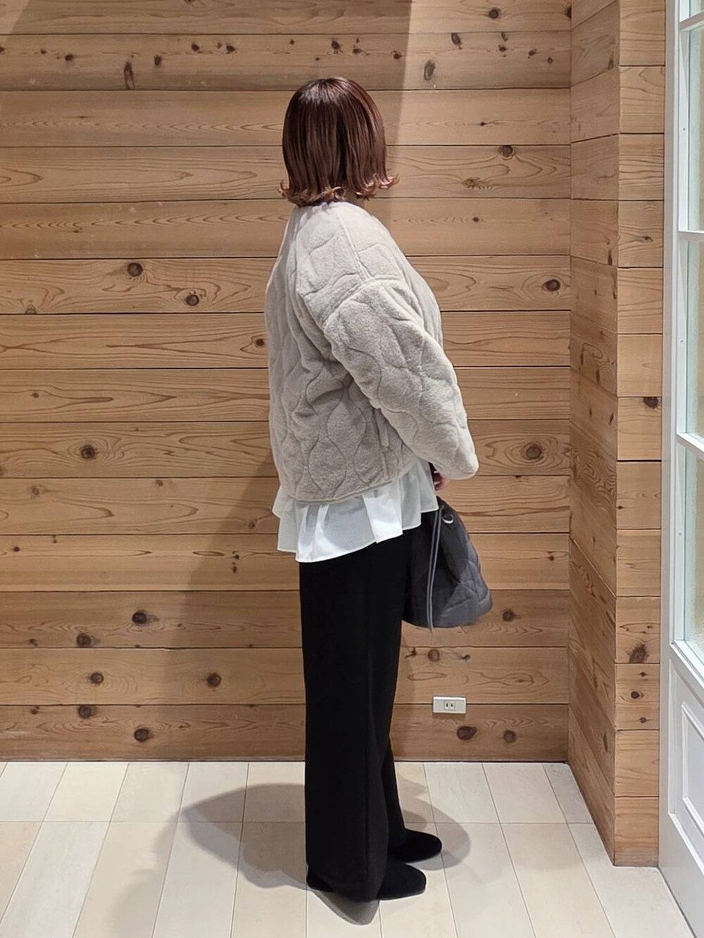 ベージュ系のブルゾン、グレー系のハンドバッグ、ブルー系のニット/セーターを着用したレディースの冬コーディネートの2枚目の写真