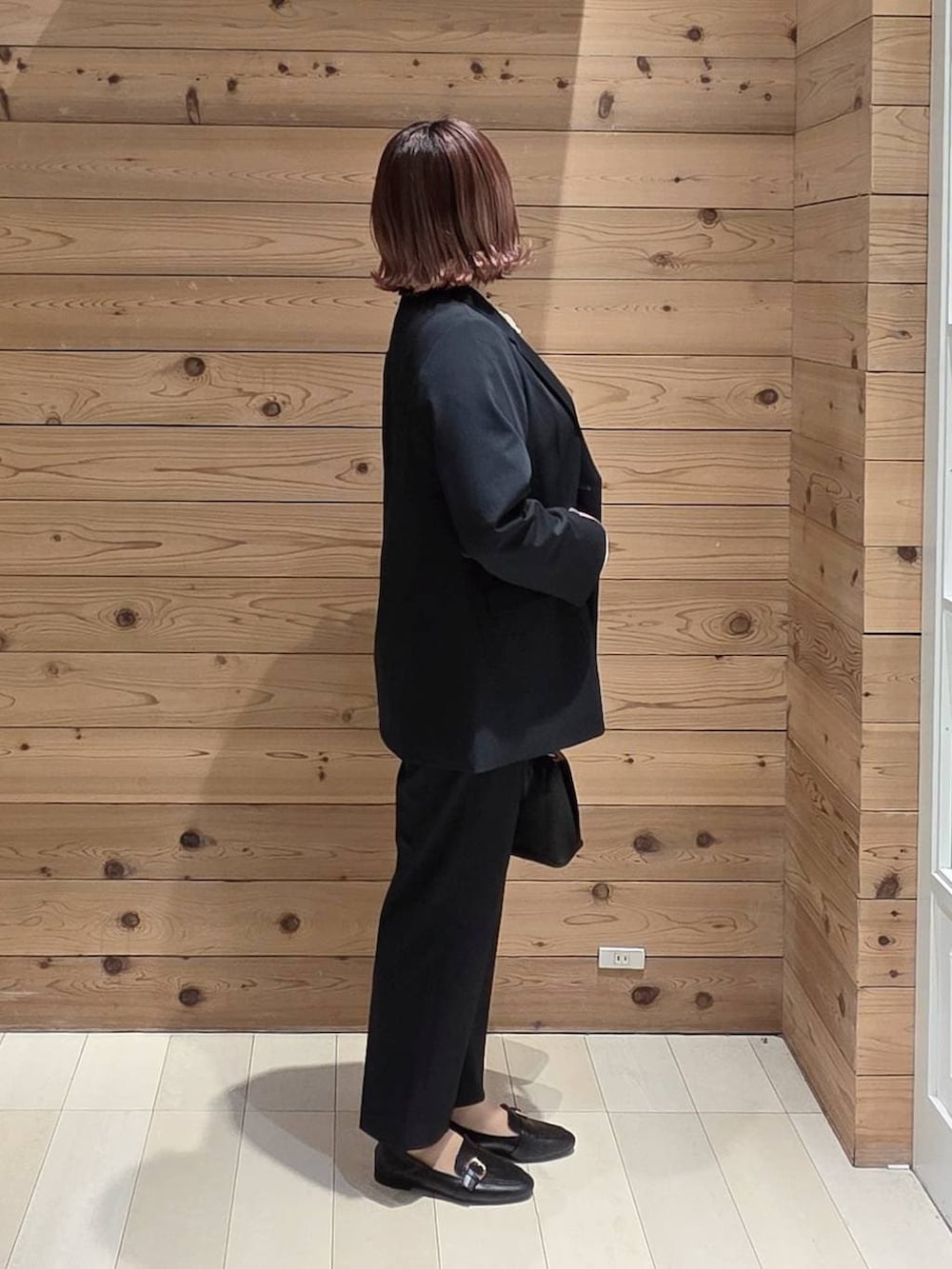 ブラック系のローファー、ブラック系のショルダーバッグ、ブラック系のスラックスを着用したレディースの春コーディネートの2枚目の写真