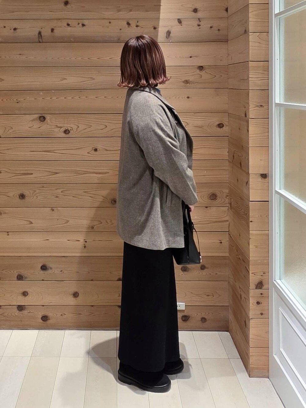 ブラック系のショルダーバッグ、ブラウン系のチェスターコート、ブルー系のシャツ/ブラウスを着用したレディースの冬コーディネートの2枚目の写真