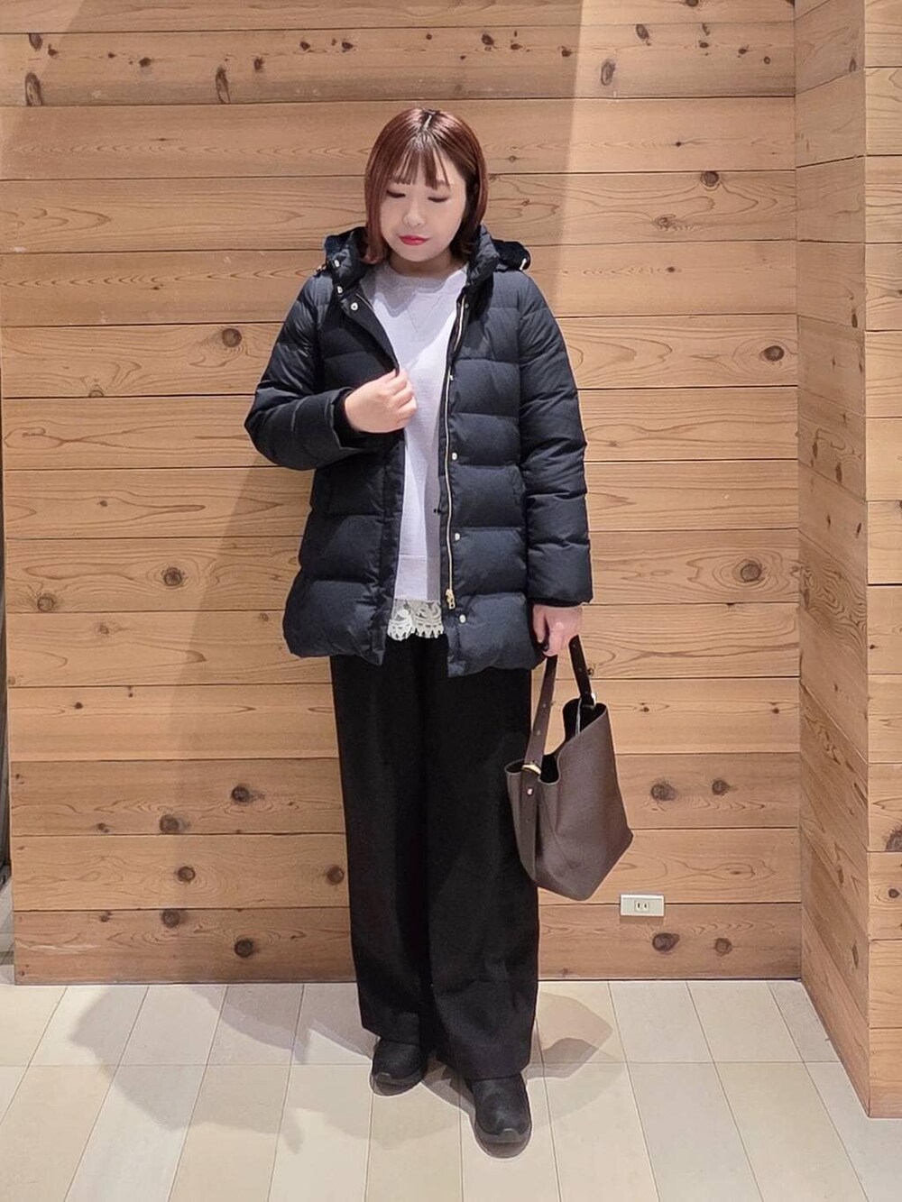 ブラウン系のショルダーバッグ、ブルー系のダウンジャケット/コート、ブラック系のブーツを着用したレディースの冬コーディネートの4枚目の写真