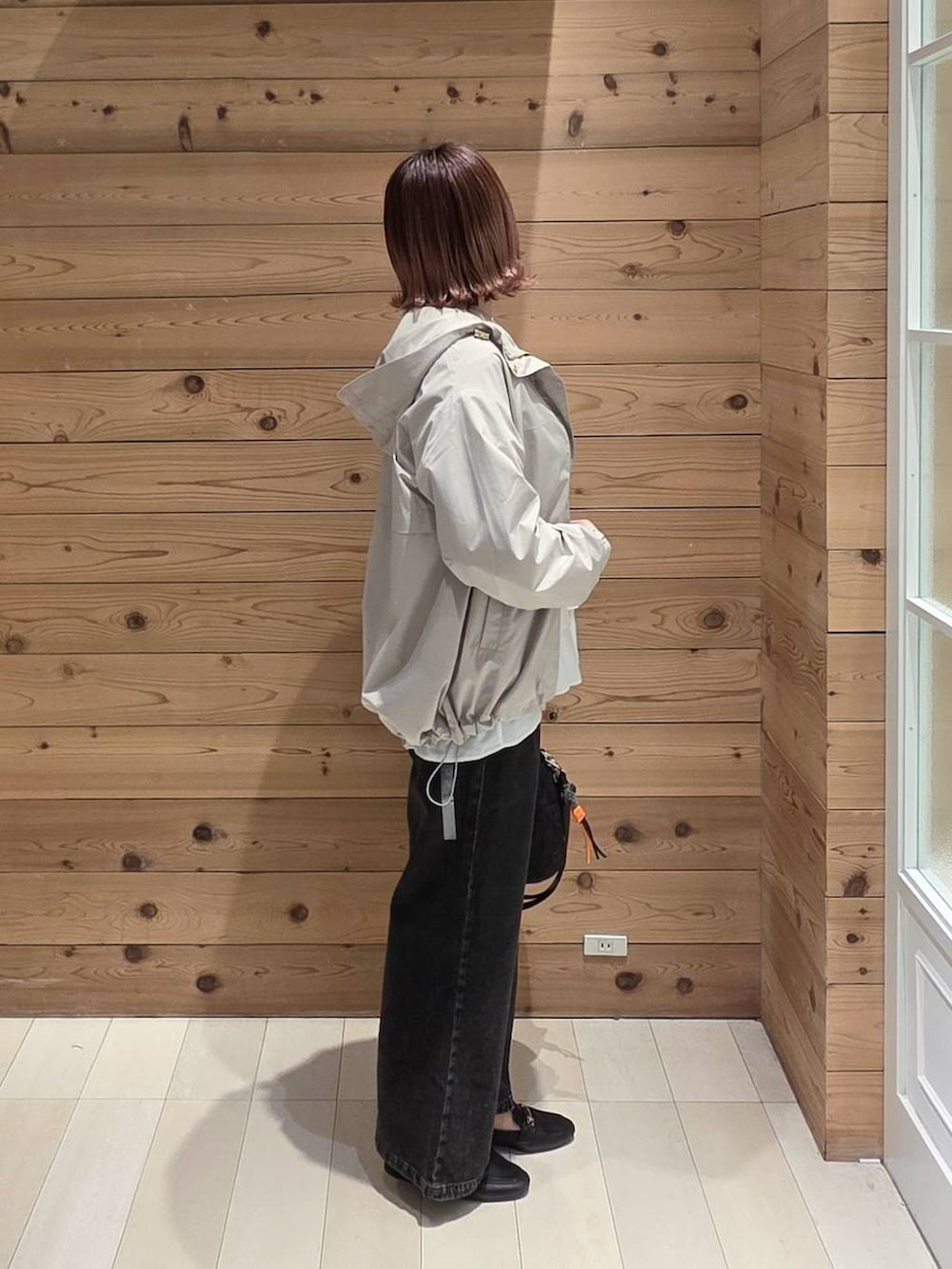 ブラック系のデニムパンツ、ブラック系のハンドバッグ、ベージュ系のマウンテンパーカーを着用したレディースの春コーディネートの2枚目の写真