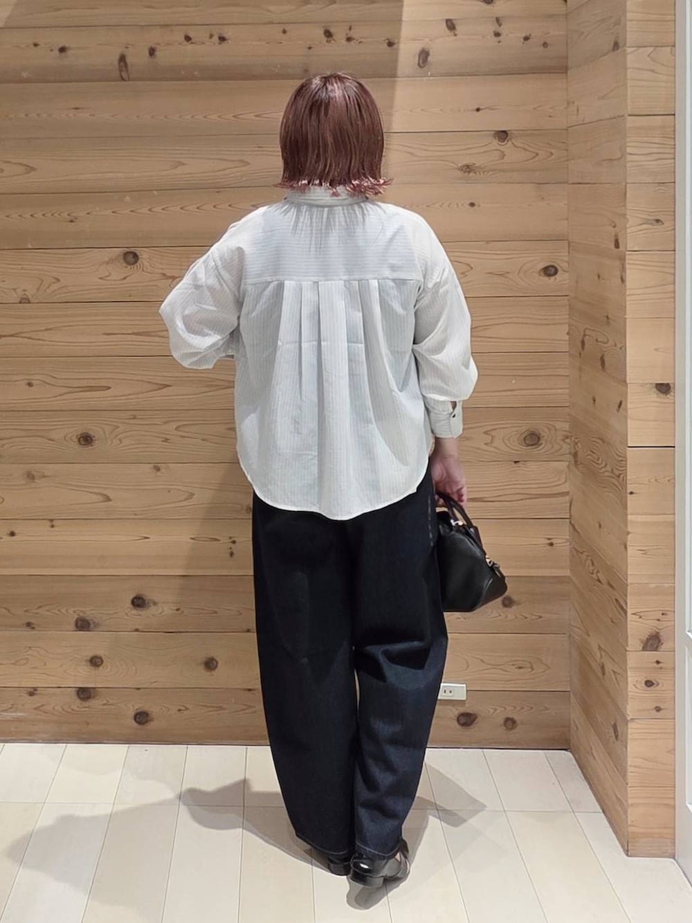 ブラック系のショルダーバッグ、ブルー系のデニムパンツ、ブラック系のタンクトップを着用したレディースの夏コーディネートの3枚目の写真