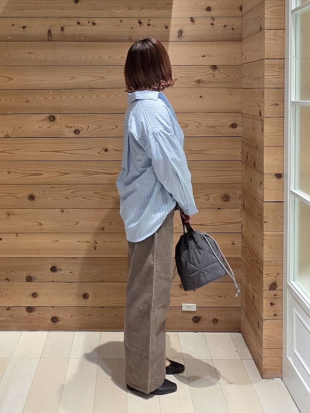 ブラック系のパンプス、ブルー系のシャツ/ブラウス、グレー系のハンドバッグを着用したレディースの春コーディネートの2枚目の写真