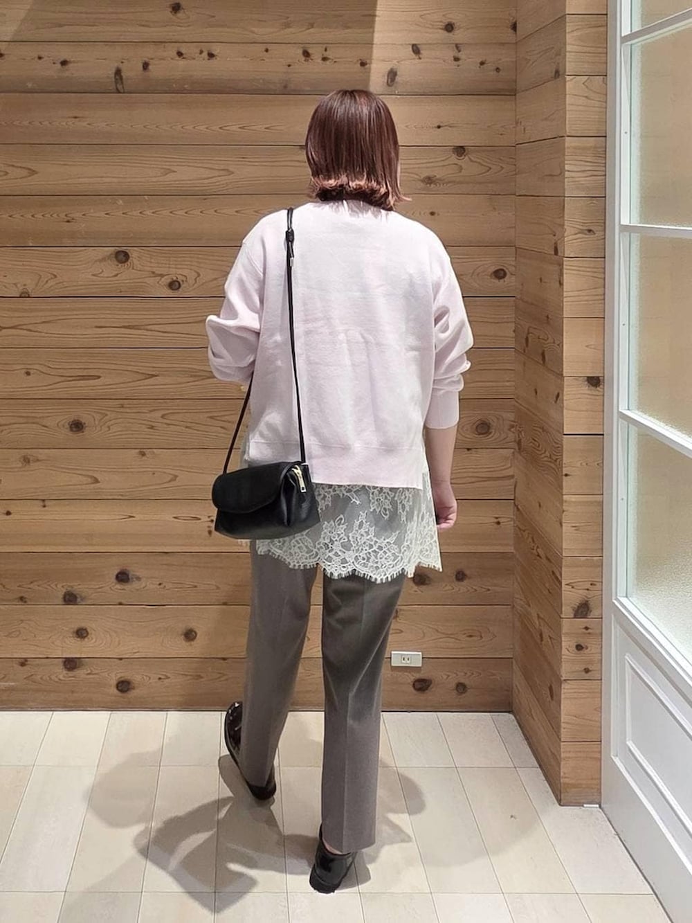 ブラック系のローファー、ブラック系のショルダーバッグ、ブラウン系のスラックスを着用したレディースの春コーディネートの3枚目の写真