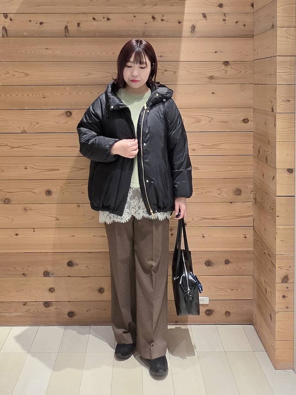 グリーン系のニット/セーター、ブラック系のダウンジャケット/コート、ブラック系のボストンバッグを着用したレディースの冬コーディネートの4枚目の写真