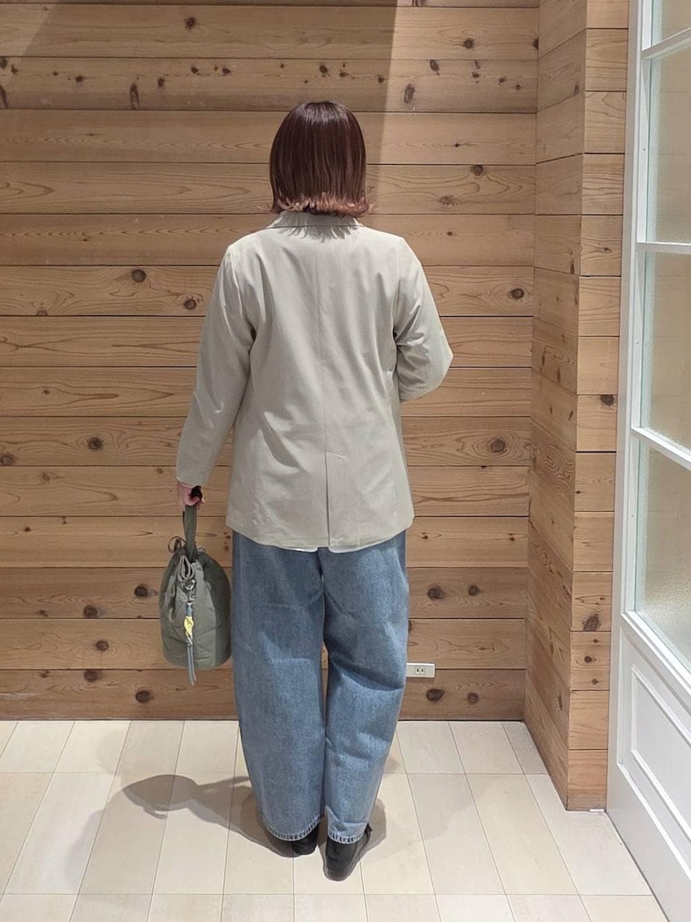 ブラック系のローファー、グリーン系のハンドバッグ、ベージュ系のテーラードジャケットを着用したレディースの春コーディネートの3枚目の写真