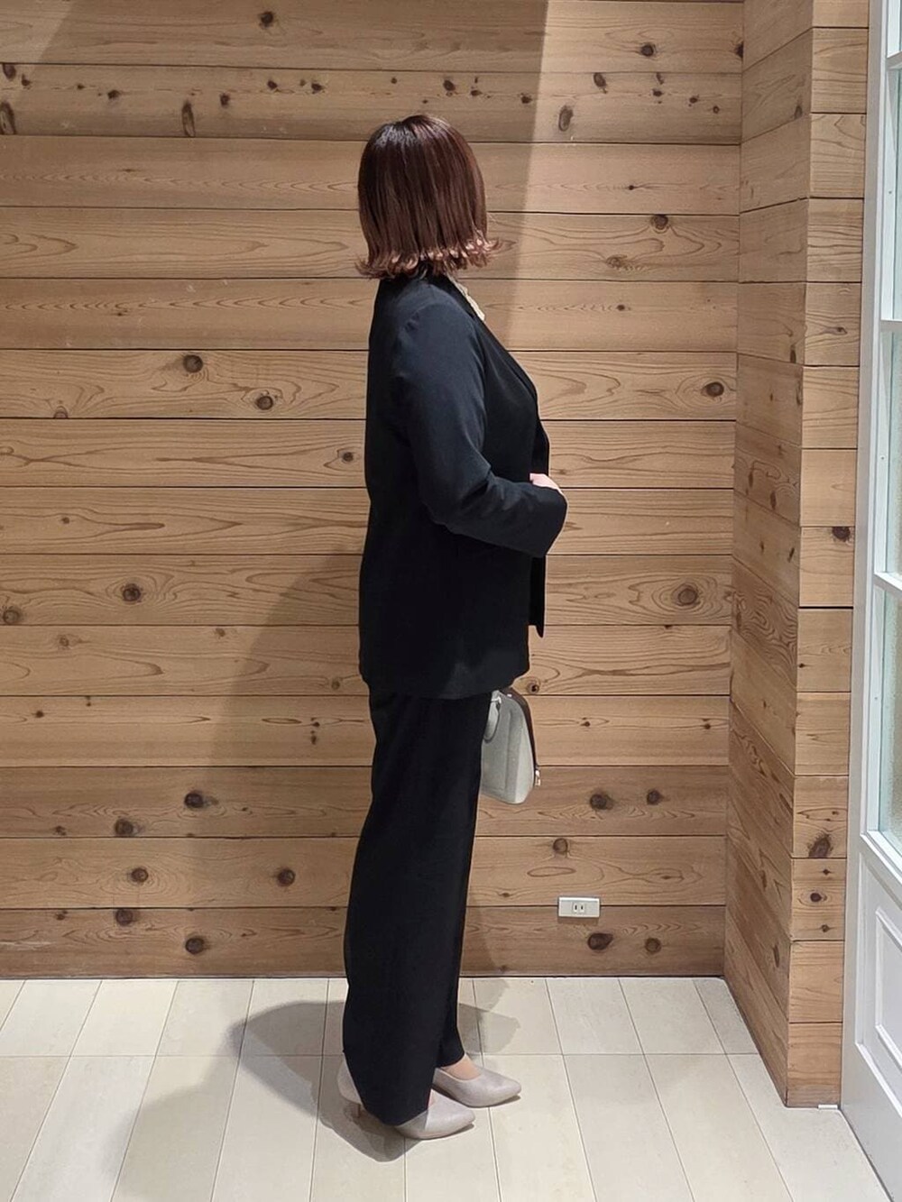 ホワイト系のショルダーバッグ、ホワイト系のパンプス、ブルー系のスラックスを着用したレディースの冬コーディネートの2枚目の写真