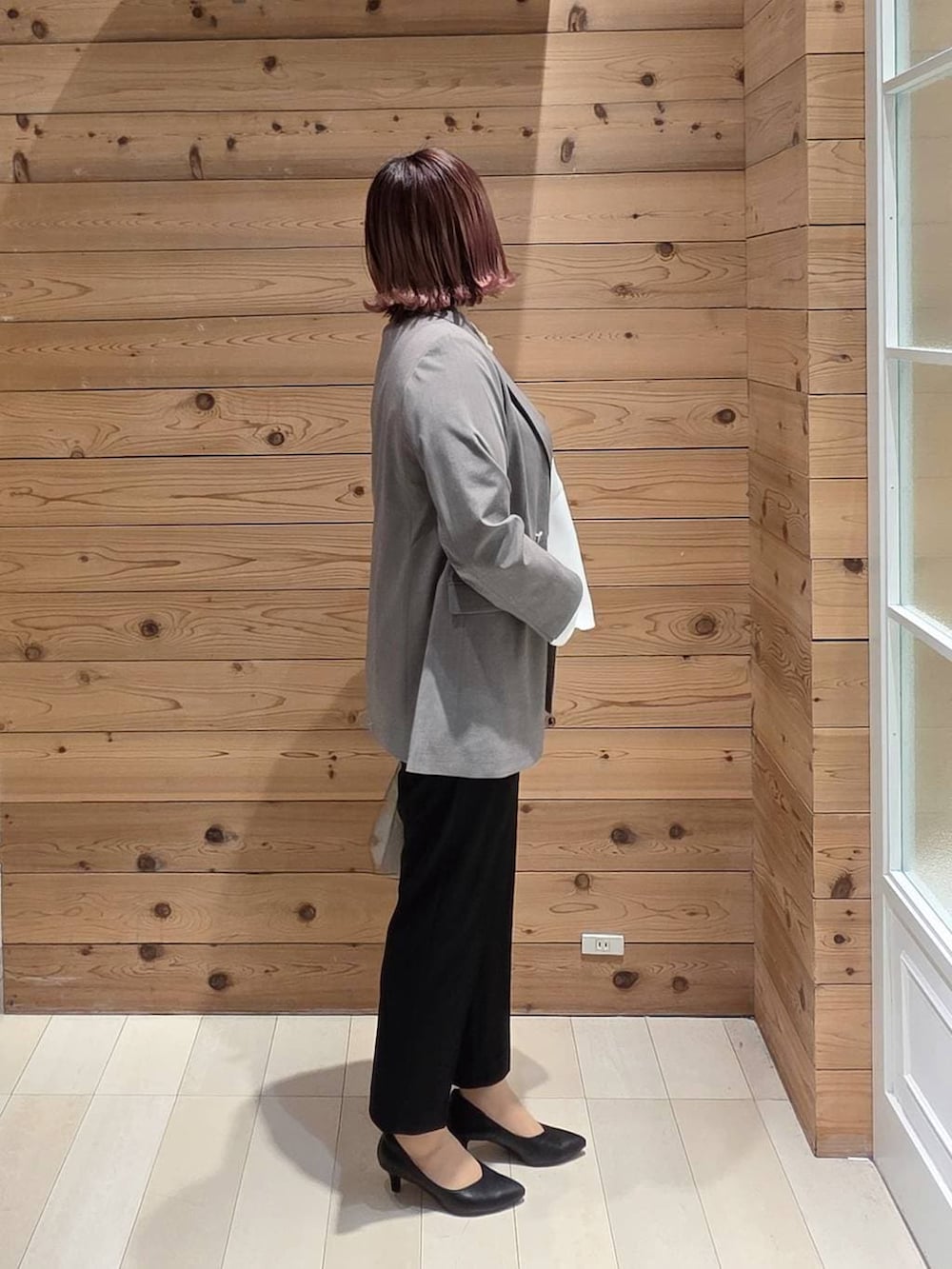 ホワイト系のショルダーバッグ、ブラック系のパンプス、ブラック系のセットアップを着用したレディースの冬コーディネートの2枚目の写真