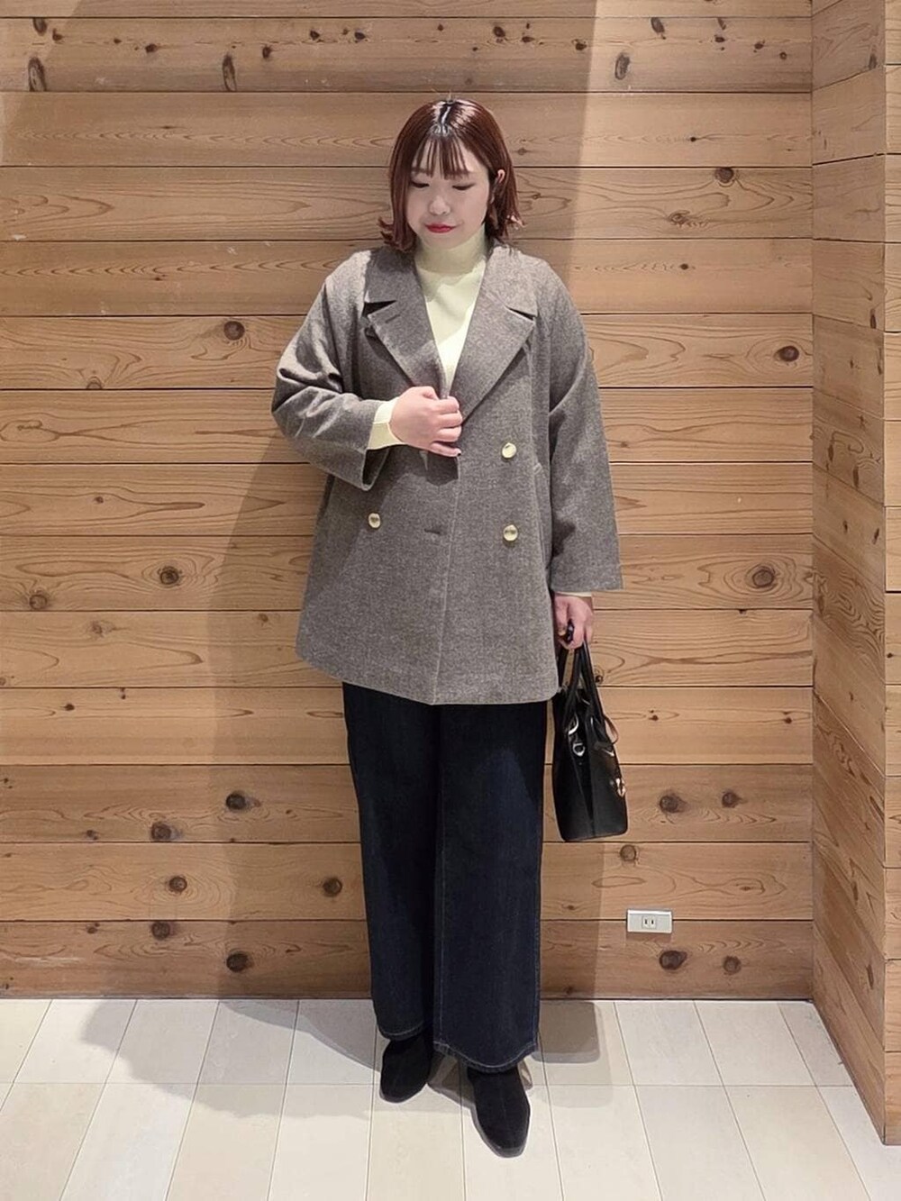 ブラック系のショルダーバッグ、ブルー系のデニムパンツ、ブラウン系のチェスターコートを着用したレディースの冬コーディネートの4枚目の写真