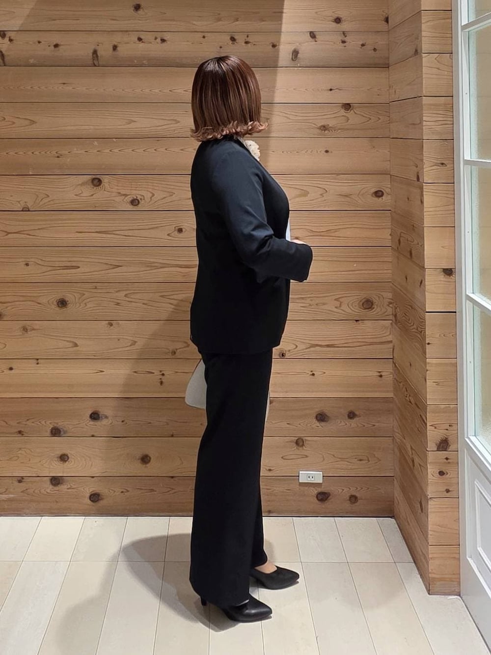 ホワイト系のショルダーバッグ、ブラック系のパンプス、ブルー系のスラックスを着用したレディースの冬コーディネートの2枚目の写真