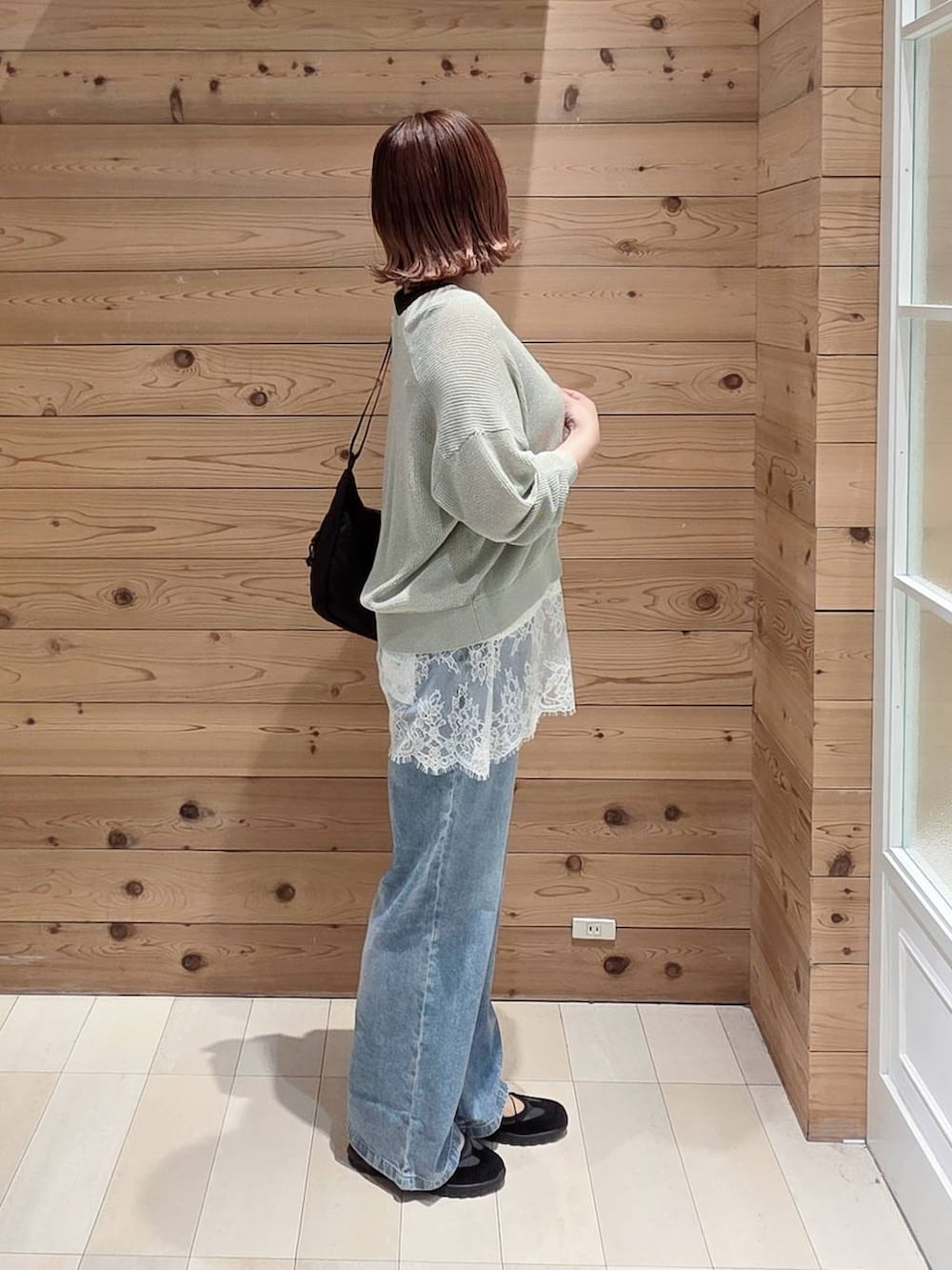 ブルー系のデニムパンツ、ブラック系のタンクトップ、グリーン系のカーディガン/ボレロを着用したレディースの春コーディネートの2枚目の写真