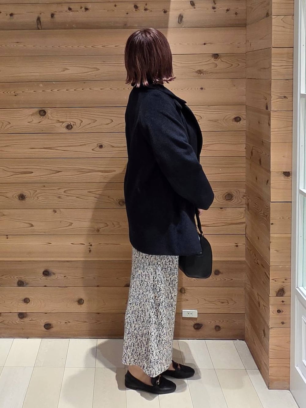 ブラック系のローファー、ブルー系のチェスターコート、グレー系のカーディガン/ボレロを着用したレディースの秋コーディネートの2枚目の写真