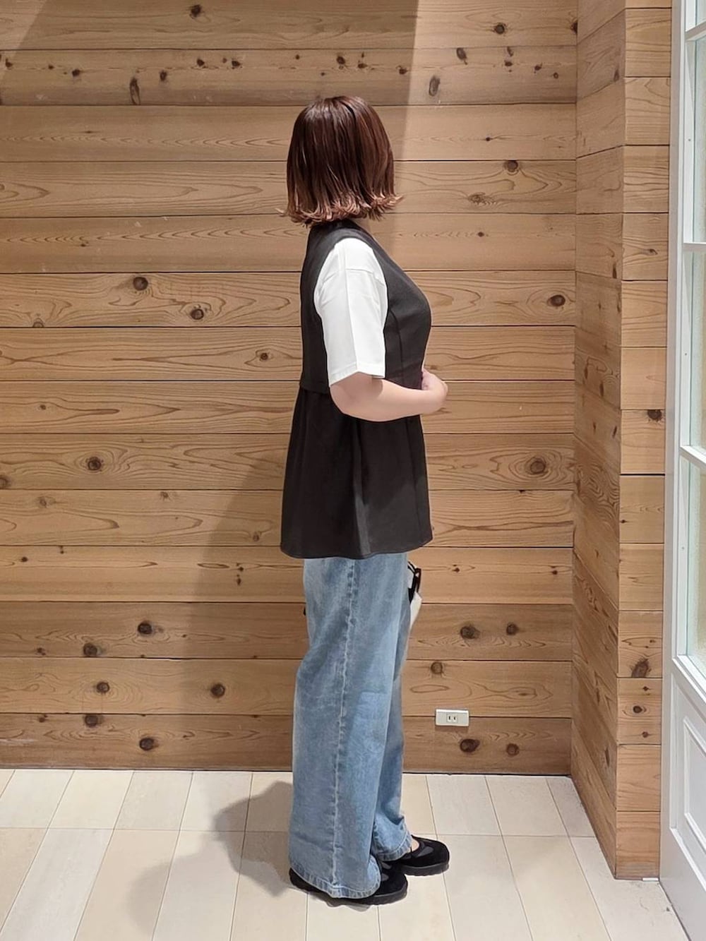 ホワイト系のボストンバッグ、グレー系のベスト、ブルー系のデニムパンツを着用したレディースの春コーディネートの2枚目の写真