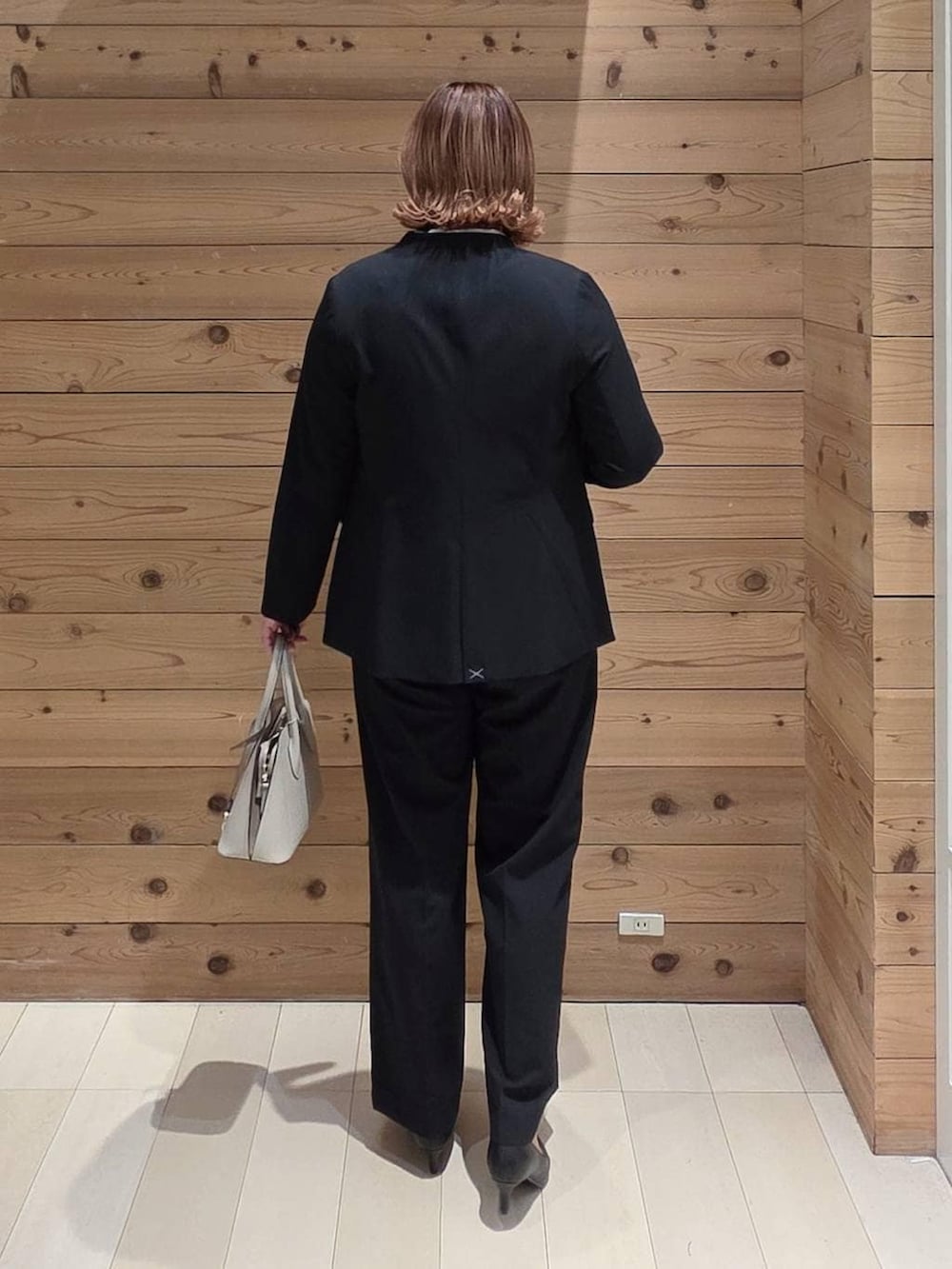 ホワイト系のショルダーバッグ、ブラック系のパンプス、ブルー系のスラックスを着用したレディースの冬コーディネートの3枚目の写真