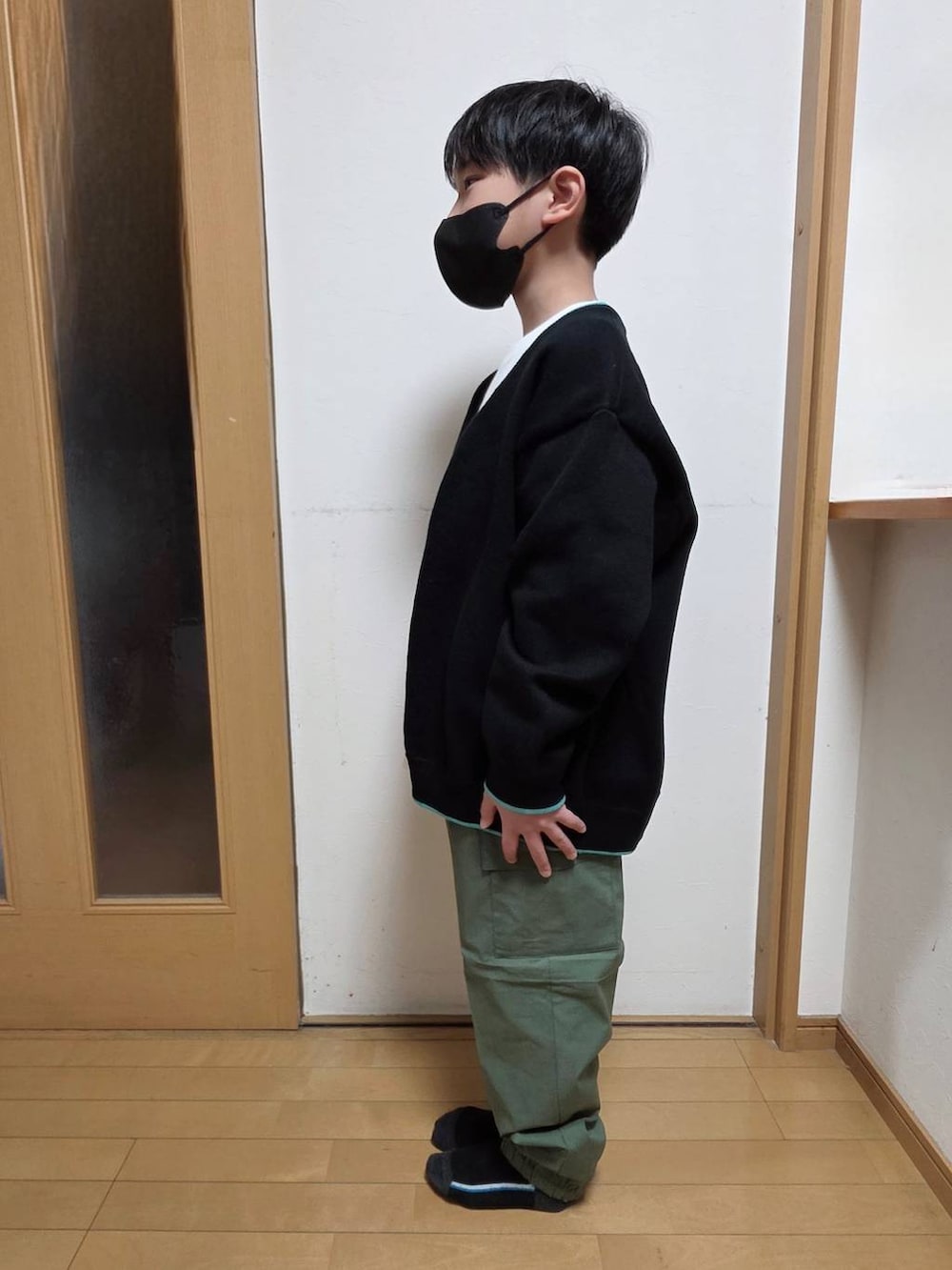 グリーン系のカーゴパンツ、ホワイト系のTシャツ/カットソー、ブラック系のニット/セーターを着用したキッズの春コーディネートの2枚目の写真